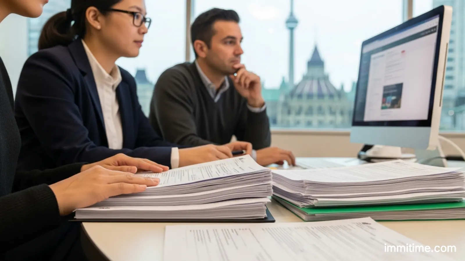 A diverse group of people looking at a presentation screen showing charts and graphs about Canadian immigration trends.